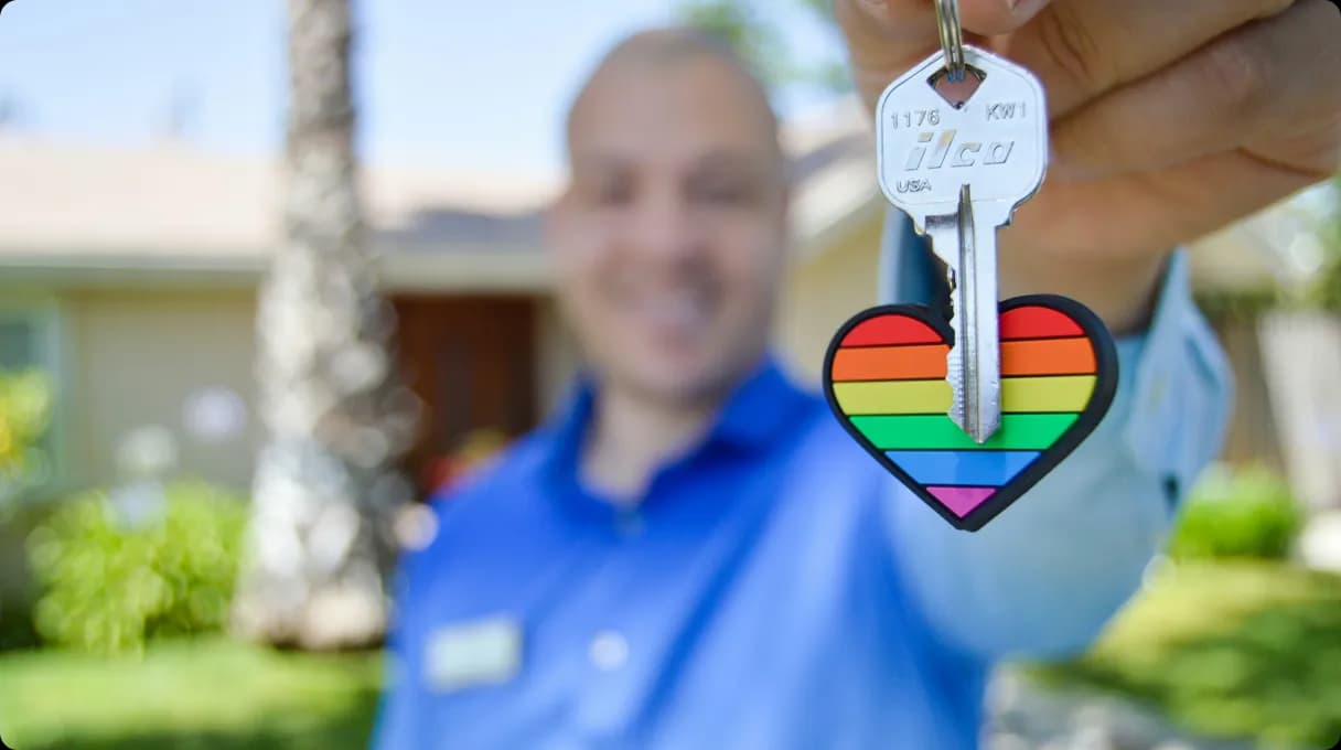Man holding a key with rainbow heart trinket