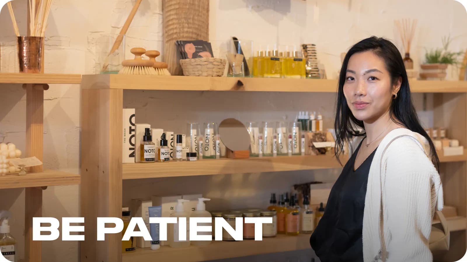 Smiling Aoxue Tang standing in the background of her products.