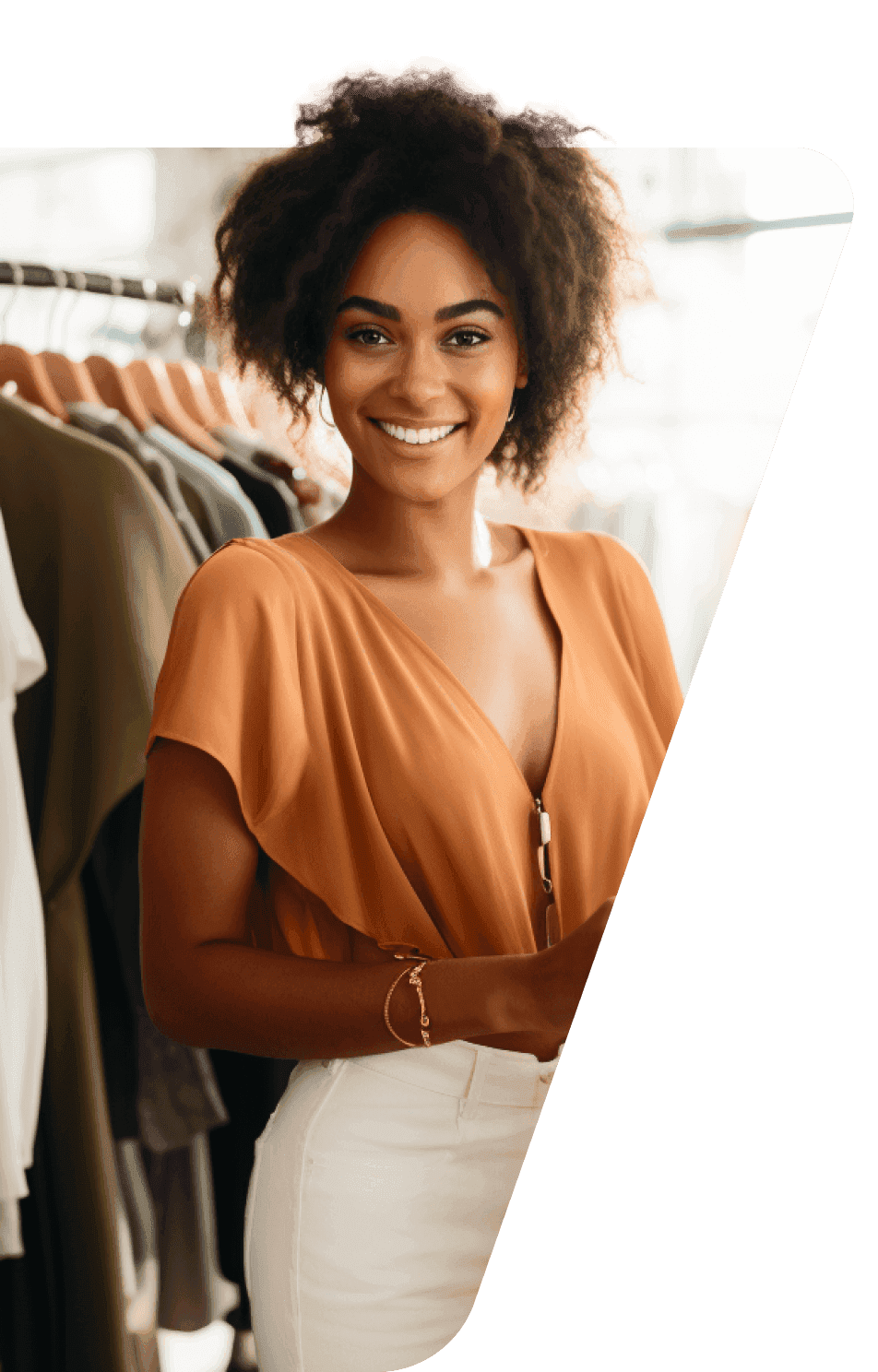 A happy woman standing in a shop full of clothes. 