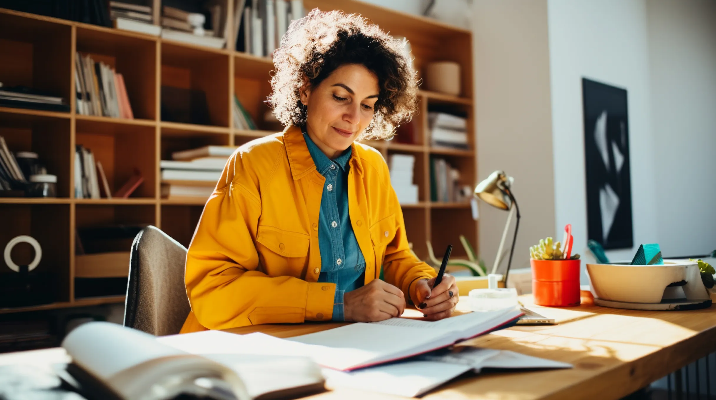 A woman is sitting at a desk and writing in a notebook.