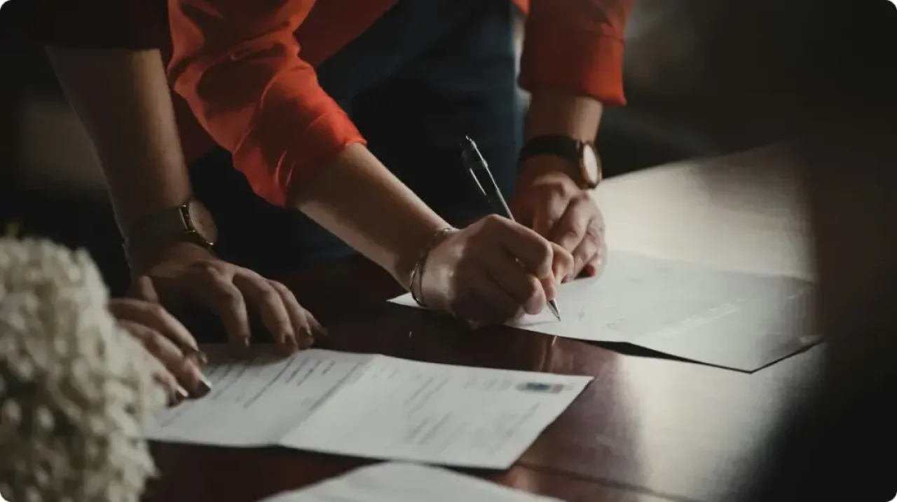 Person-in-orange-long-sleeve-shirt-writing-on-white-paper