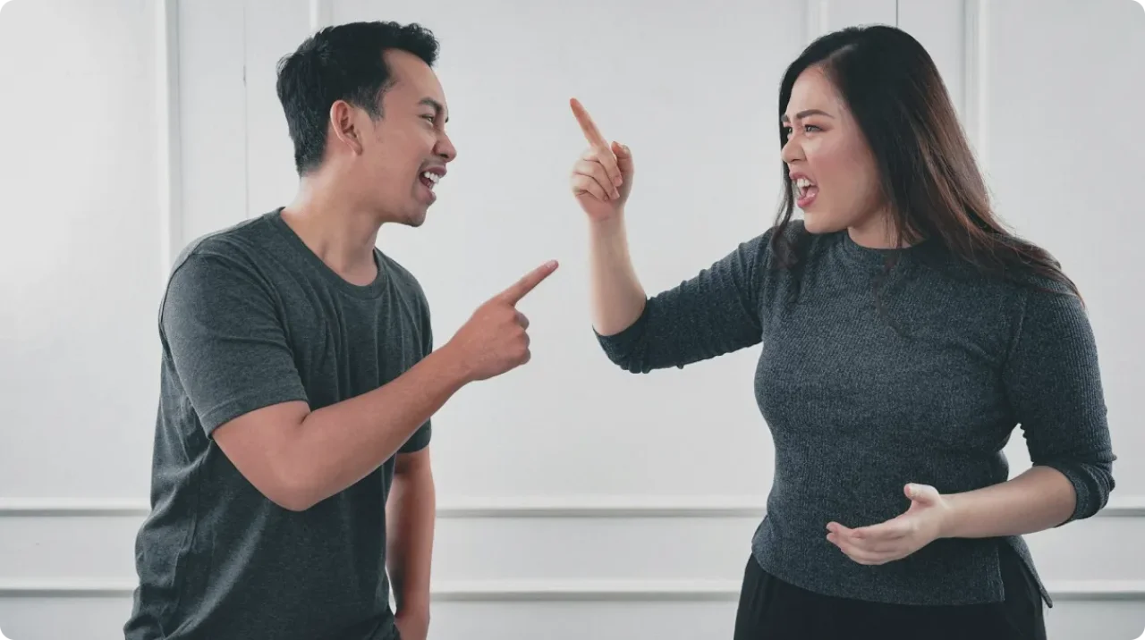 Man in gray crew neck shirt arguing with woman in black crew neck long sleeve shirt